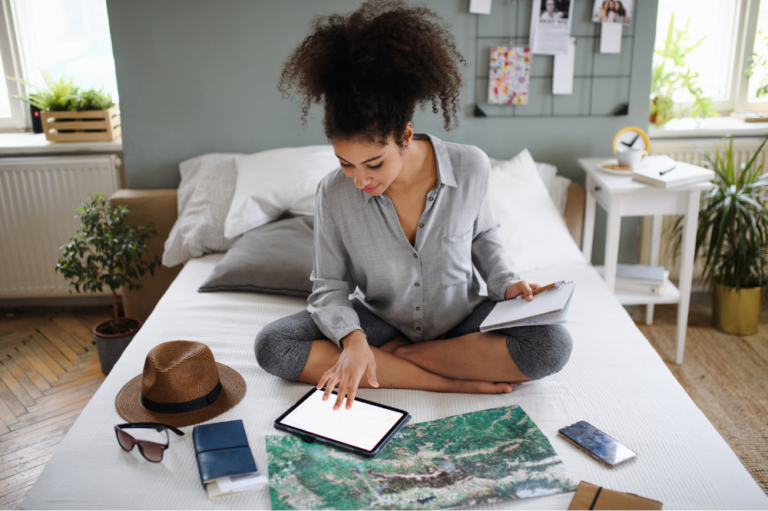 Woman sitting on bed planning vacation time.