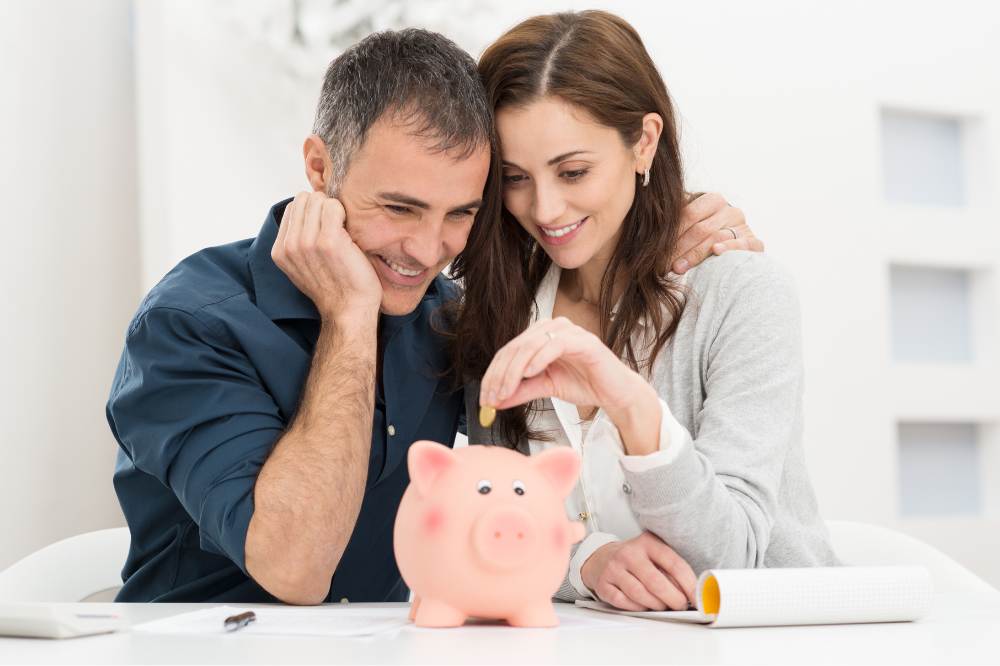 A couple putting money into a money box.